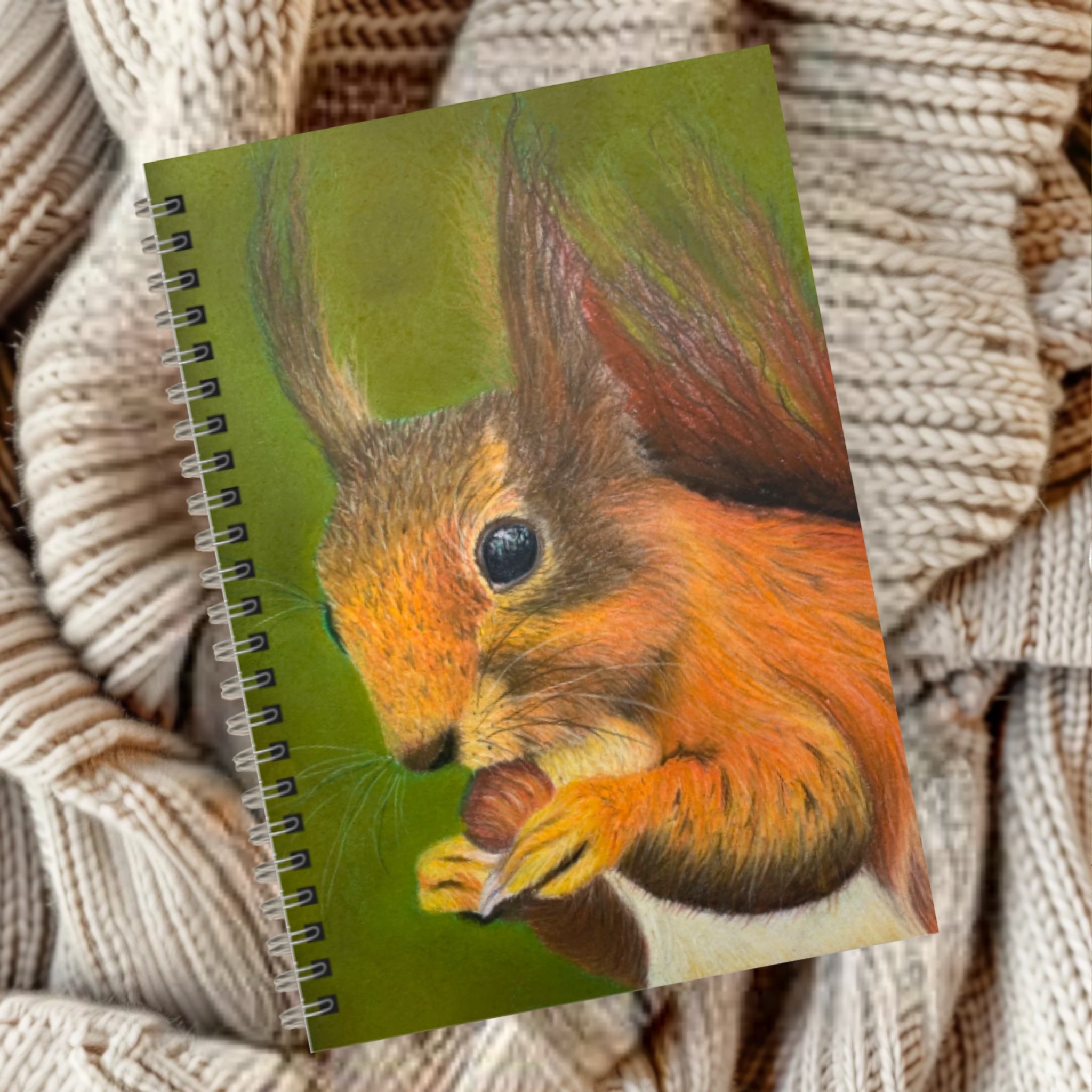 Notebook with a red squirrel eating a nut illustration on a green background