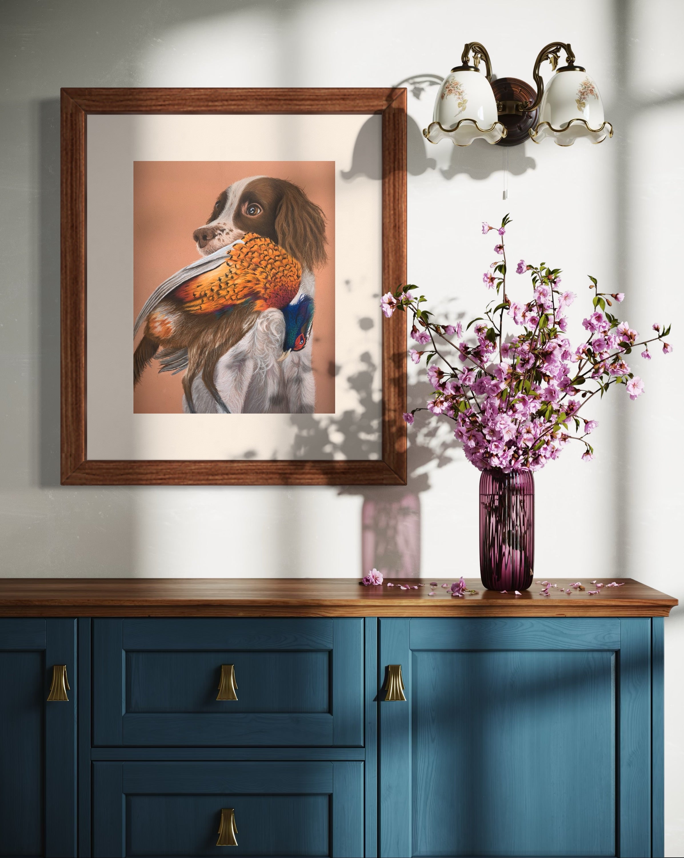 Framed artwork of a springer spaniel holding a pheasant hung on a wall